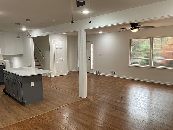 View from dining room into the kitchen and living room. Stairs going up to bedrooms.