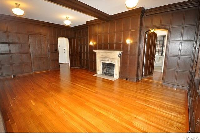 Wood paneled library / fourth Bedroom / home office / den with wood burning fireplace, coffered ceiling, built-in bookcases, walk-in closet and refinished hardwood floors.  The room is 21'-9" x 14'-9"