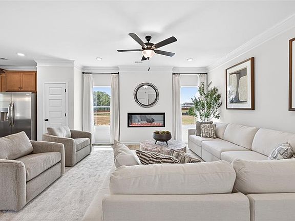 Spacious living area featuring a modern linear fireplace, large windows, crown molding, a ceiling fa