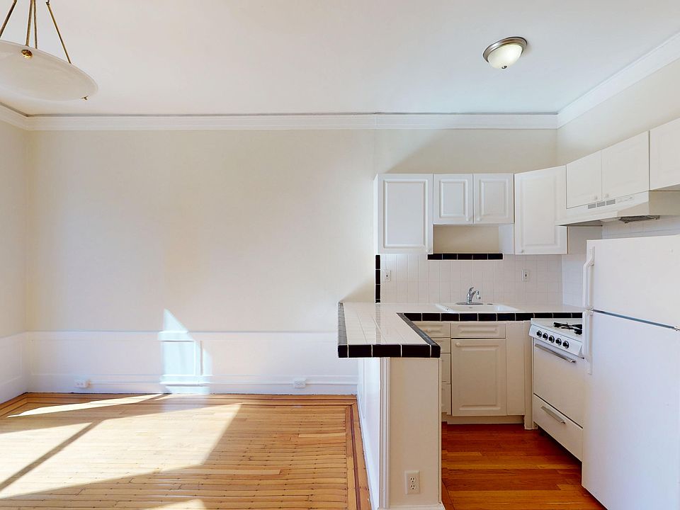 Bright, airy kitchen featuring cabinetry, a tile countertop, and wooden floors, with natural light streaming in.