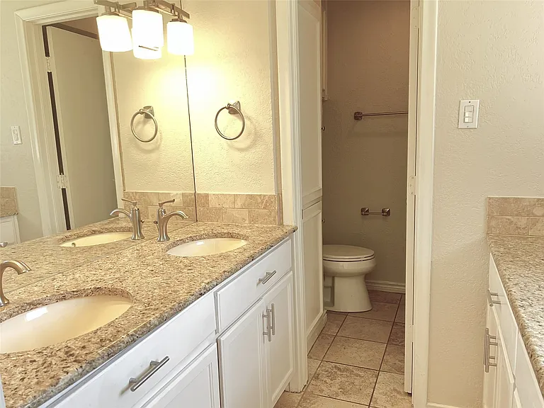 Double vanity with granite countertops, dual undermount sinks, and brushed nickel faucets
