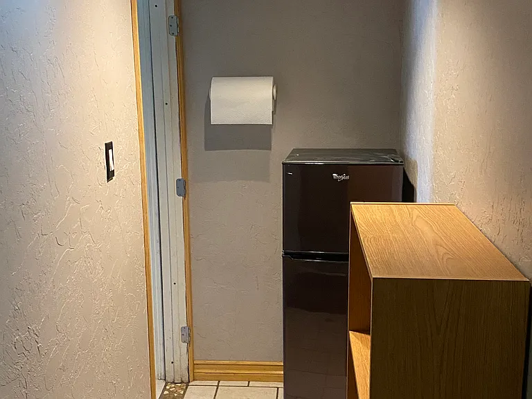 Fridge and tiled hallway, with beautiful wood trim, to bedroom.