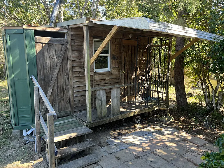 Very small tiny house on wheels in secluded area with bathroom.