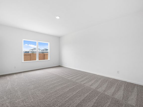 Expansive master bedroom with tan carpet and windows.