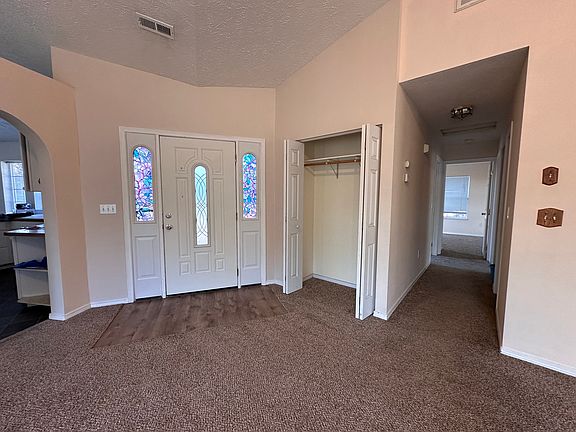 Inside view from the living room with the kitchen on the left, entry door in the center, and hallway to 3 bedrooms and a bathroom.