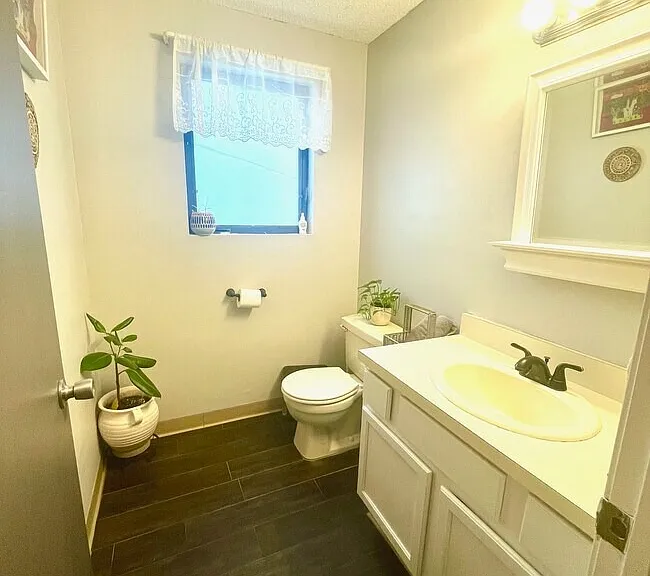 Half bathroom with dark flooring, toilet, and pedestal sink.