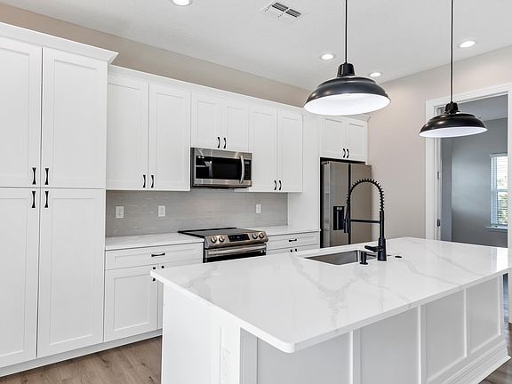 View of most of the kitchen that includes the island, cabinets, and appliances. Facing north east.
