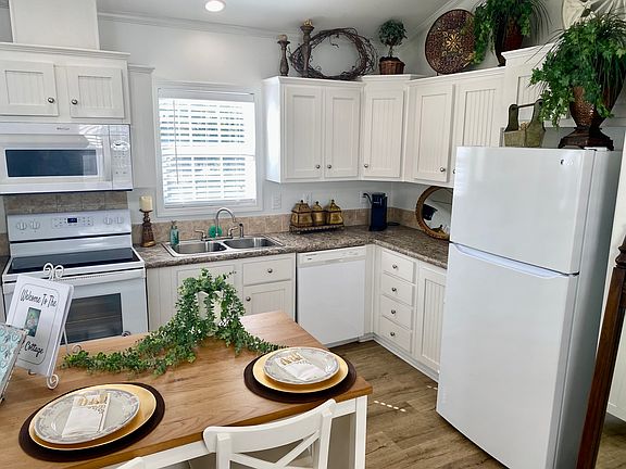 Kitchen featuring white appliances, wood counters, white cabinetry, lofted ceiling, and wood finished floors. The island is great for prepping food or enjoying a quick meal. Fridge included.