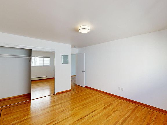 Bright bedroom with wood-like floor and a closet with mirror