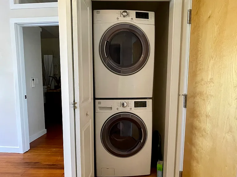 Stacked washer/dryer closet opposite bathroom.