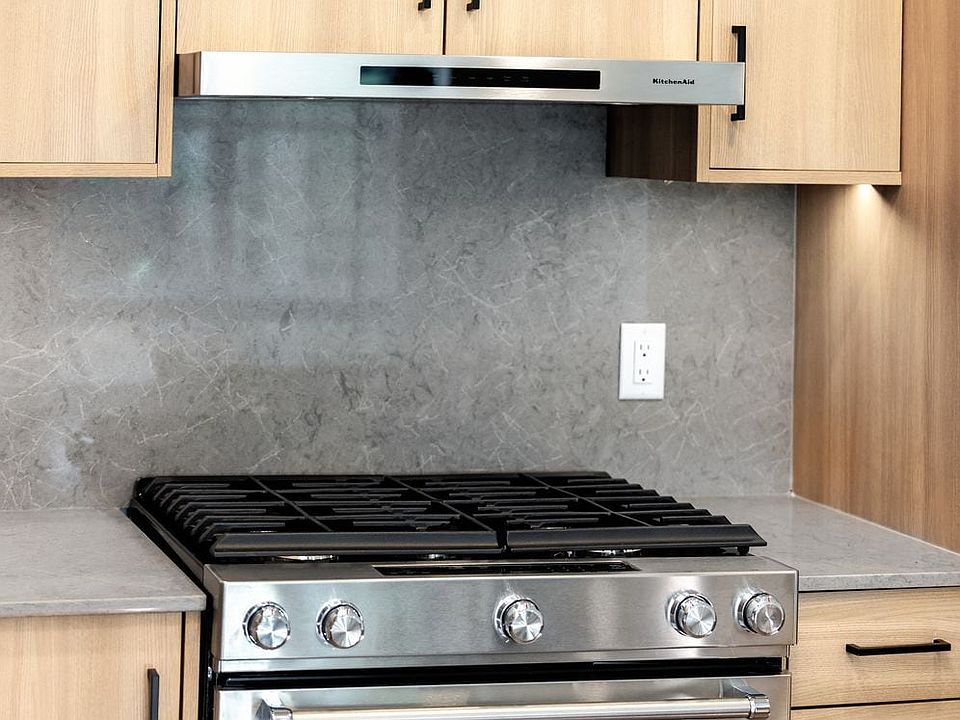 Signature Collection kitchen with stainless steel appliances, quartz countertops, and quartz tile backsplash