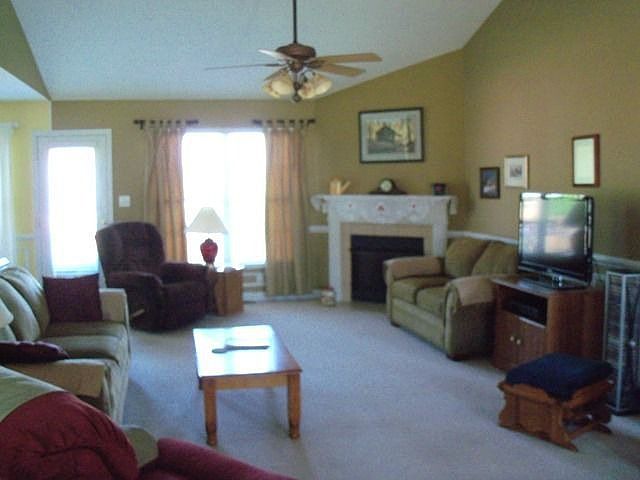 Living room with vaulted ceiling and a fireplace.
