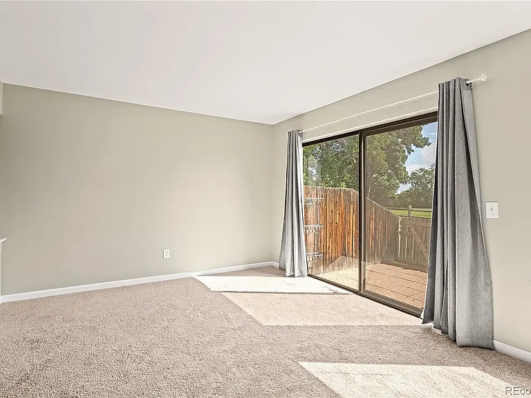 Living area with sliding door to porch. Porch looks out onto walking path and well-maintained green belt.