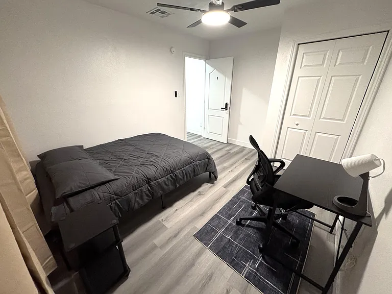 Private bedroom with a full bed, dedicated desk/work area, ceiling fan, and roomy closet for everyday storage.