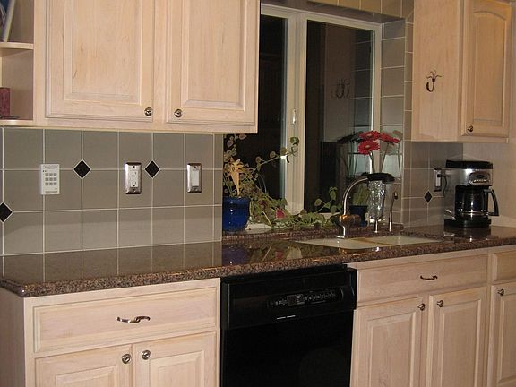 Granite slab counters, maple cabinets, and matching black appliances.