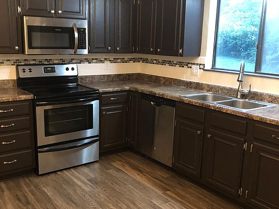 Remodeled kitchen with tiled backsplash and stainless steel appliances