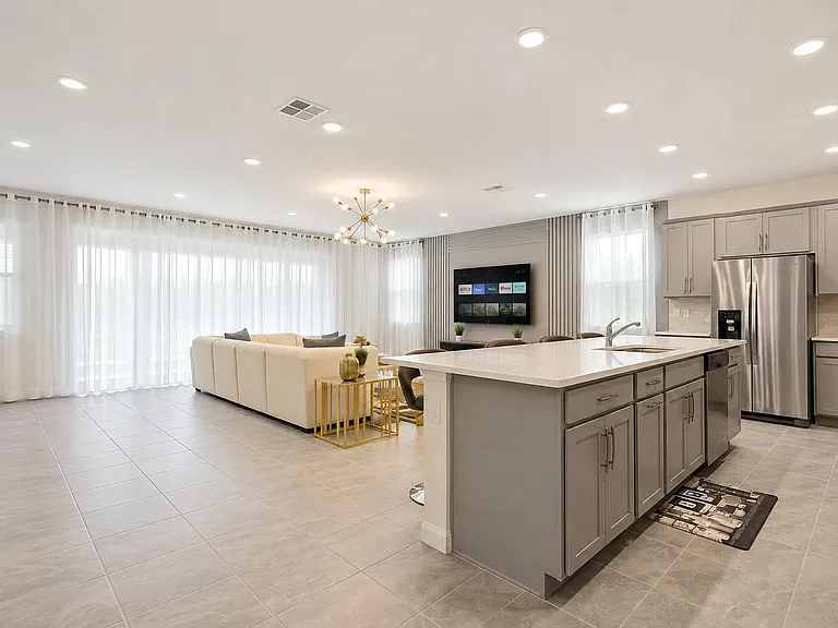 Open-concept kitchen and living area with a large island, ample cabinetry, stainless appliances, and oversized windows.