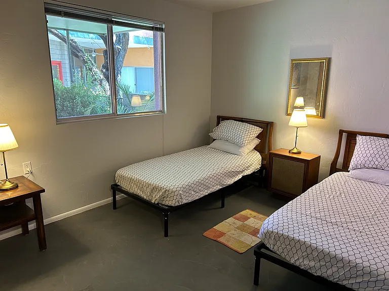 View of the second bedroom with twin beds and window to the garden.