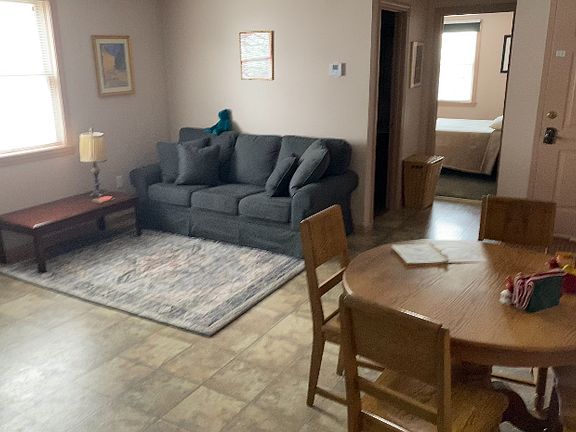 Kitchen/livingroom with table and four chairs, coffee table, very comfy couch and plush area rug.