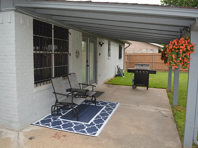 Covered patio area with outdoor furniture and a BBQ grill.