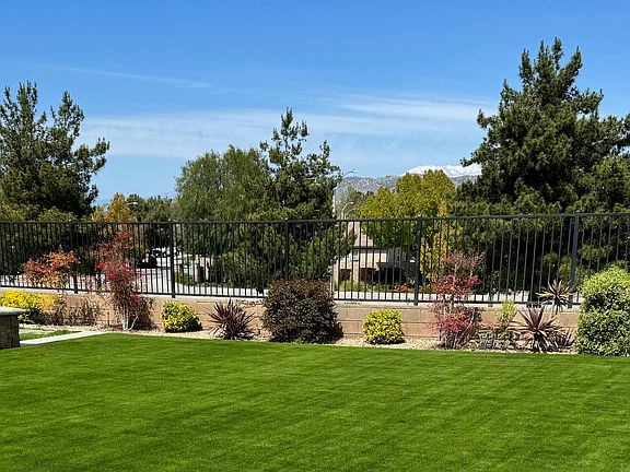 Partial backyard view: Step outside to your private outdoor oasis featuring lush turf, mountain views, and a fully cemented patio designed for relaxation and entertainment.