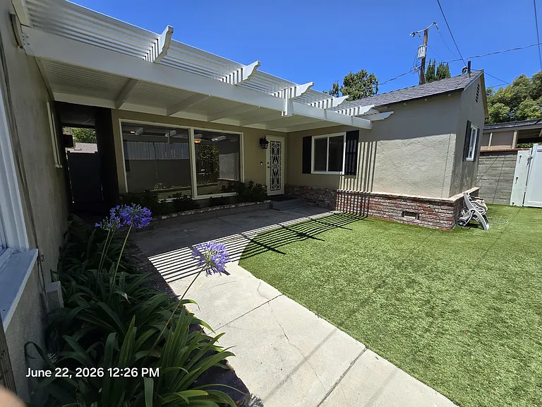 Great view of yard, vinyl patio, patio, walkway and mature flower beds. Area private from street and just steps from one carport parking plus garage parking. Very private area.