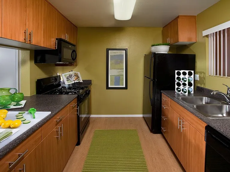 Classic Package kitchen with black appliances, grey speckled laminate countertops, oak cabinetry, and hard surface flooring