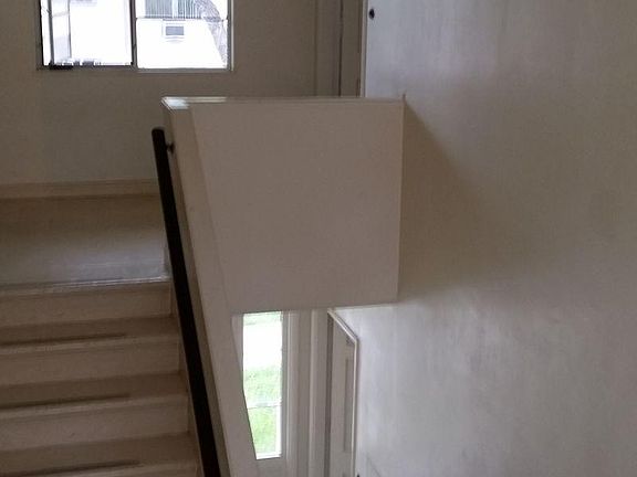 Stairs going upstairs. Entrance shown at the top right of photo.