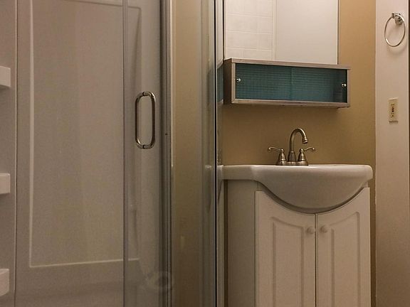Bathroom has a standing shower, fan/vent, window, and walk-in area for a drying rack or additional shelving.