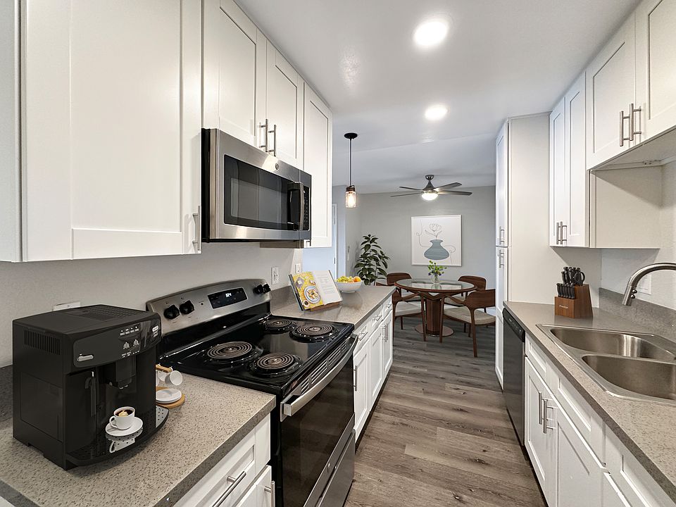 Upgraded kitchen with white shaker-front cabinets, gray quartz counters, and stainless steel appliances.