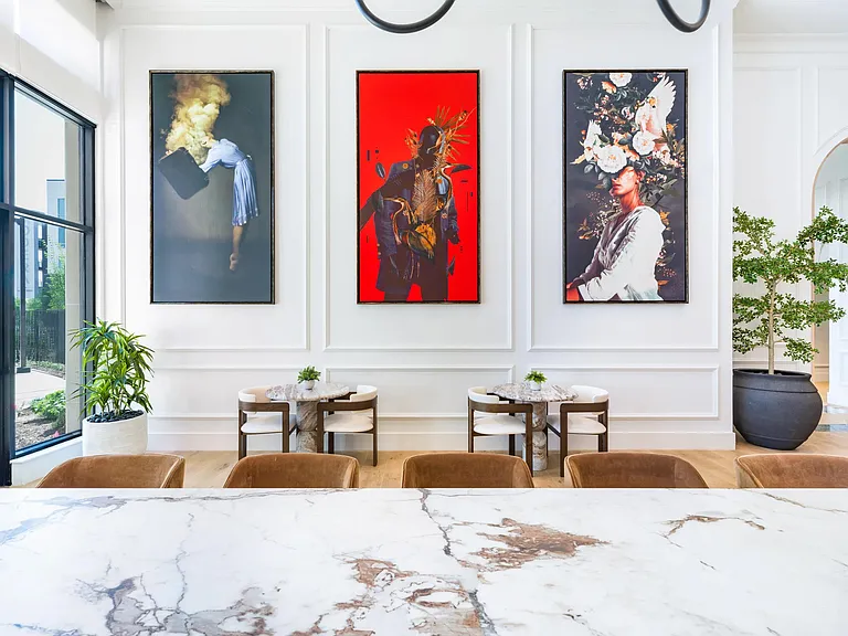 Art-lined community lounge with cafe seating and marble-topped tables, reflecting Nashville's creative spirit and gallery-inspired design.