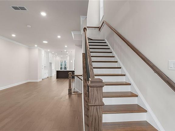 Stairway with recessed lighting, hardwood wood-style flooring, and crown molding