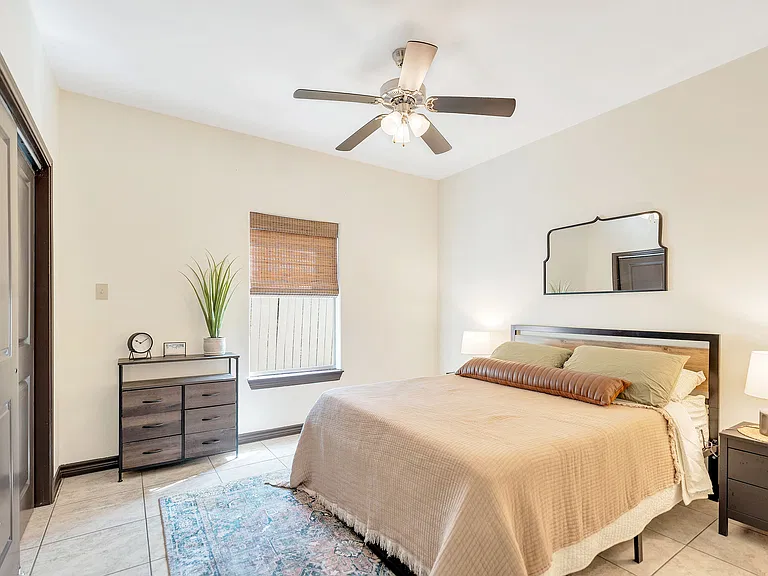 A cozy bedroom featuring a bed, dresser, and ceiling fan at La Joya Apartments in Laredo, Texas