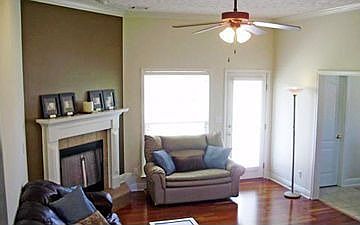 Great room with wood floors and fireplace nestled in the corner.