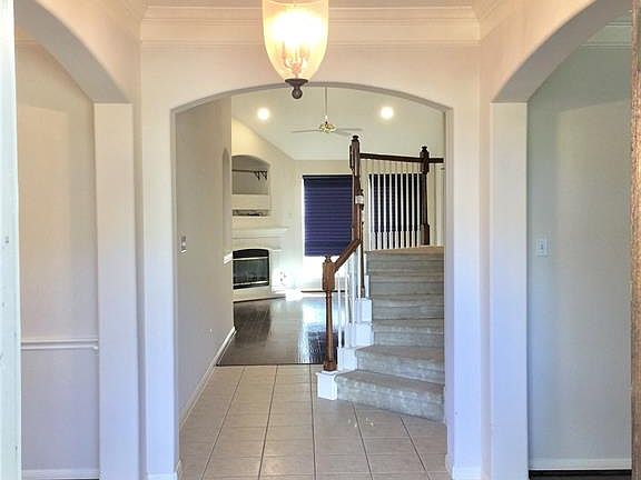 Front tiled entry foyer looking towards family with dining left and living/flex room right. They both have beautiful wood floors.
