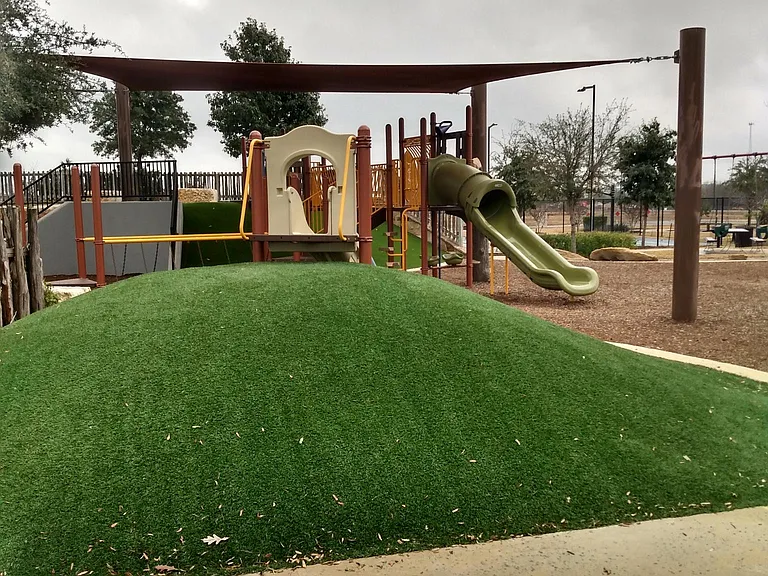 Playground with lighted tennis courts in the background