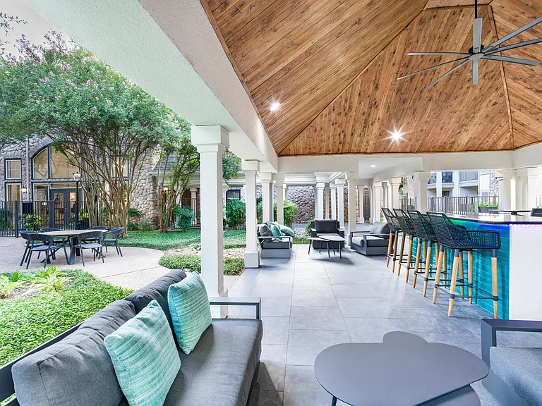 Lounge under the pavilion with comfortable seating, a ceiling fan, and a vibrant poolside bar just steps away.