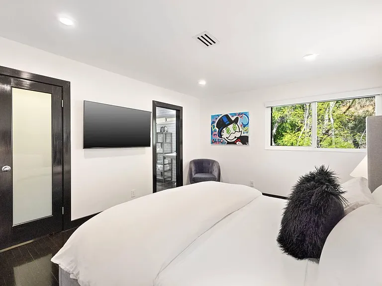 Unwind in our modern bedroom, featuring a king-size bed and a flat-screen TV.
