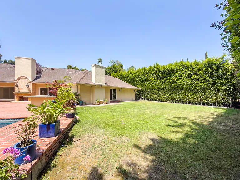 Expansive side yard with a manicured lawn and tall hedges offers privacy at this Beverly Hills luxury rental, 1094 Garden Lane, a 90210 lease.