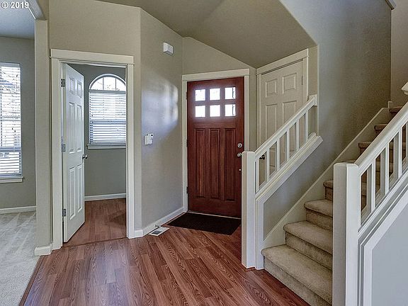Featuring Main entrance door with shiny hardwood flooring and a large storage room on the right with a white door before the staircase.