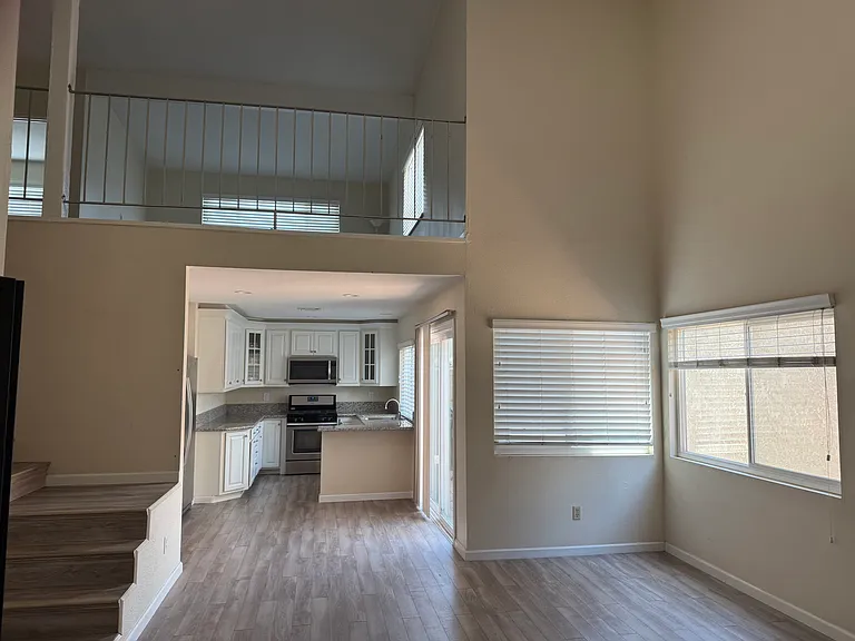 Open living space area on the first floor with vaulted ceilings with views of back patio area and second floor loft.