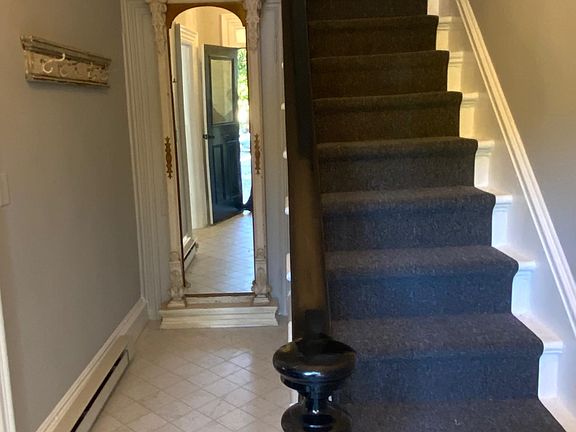 Private hall way with coat rack and stairs to apartment.