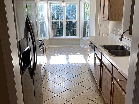 Kitchen with stainless steel refrigerator flows to breakfast area.