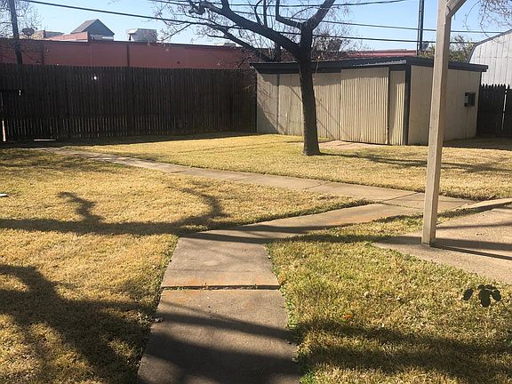 Back yard with large work shop (with lights and electricity), wooden fence with gates and covered patio.
