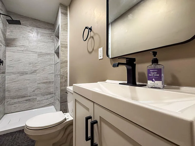 Updated bathroom with a tiled shower, built-in niche shelving, and a vanity with ample counter space and storage.