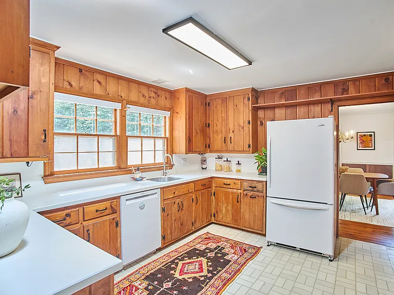 The kitchen has generous cabinet space and a view of the woods.