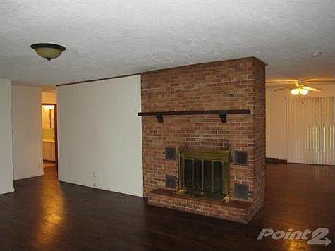 Open design has a spacious Living Room with wood burning fireplace and hardwood flooring.