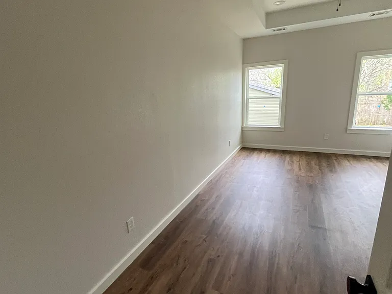 L-shaped Primary Bedroom features Tray ceiling and fan