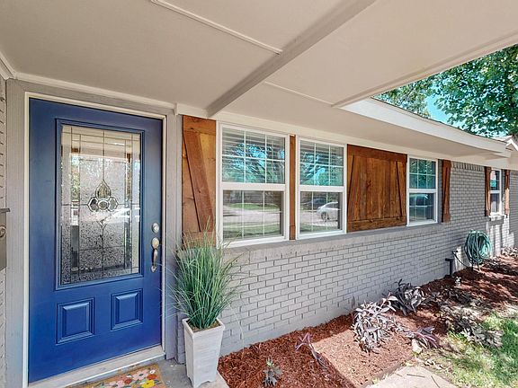 A cheerful pop of blue greets you at the front door, framed by fresh landscaping and rustic wood shutters.