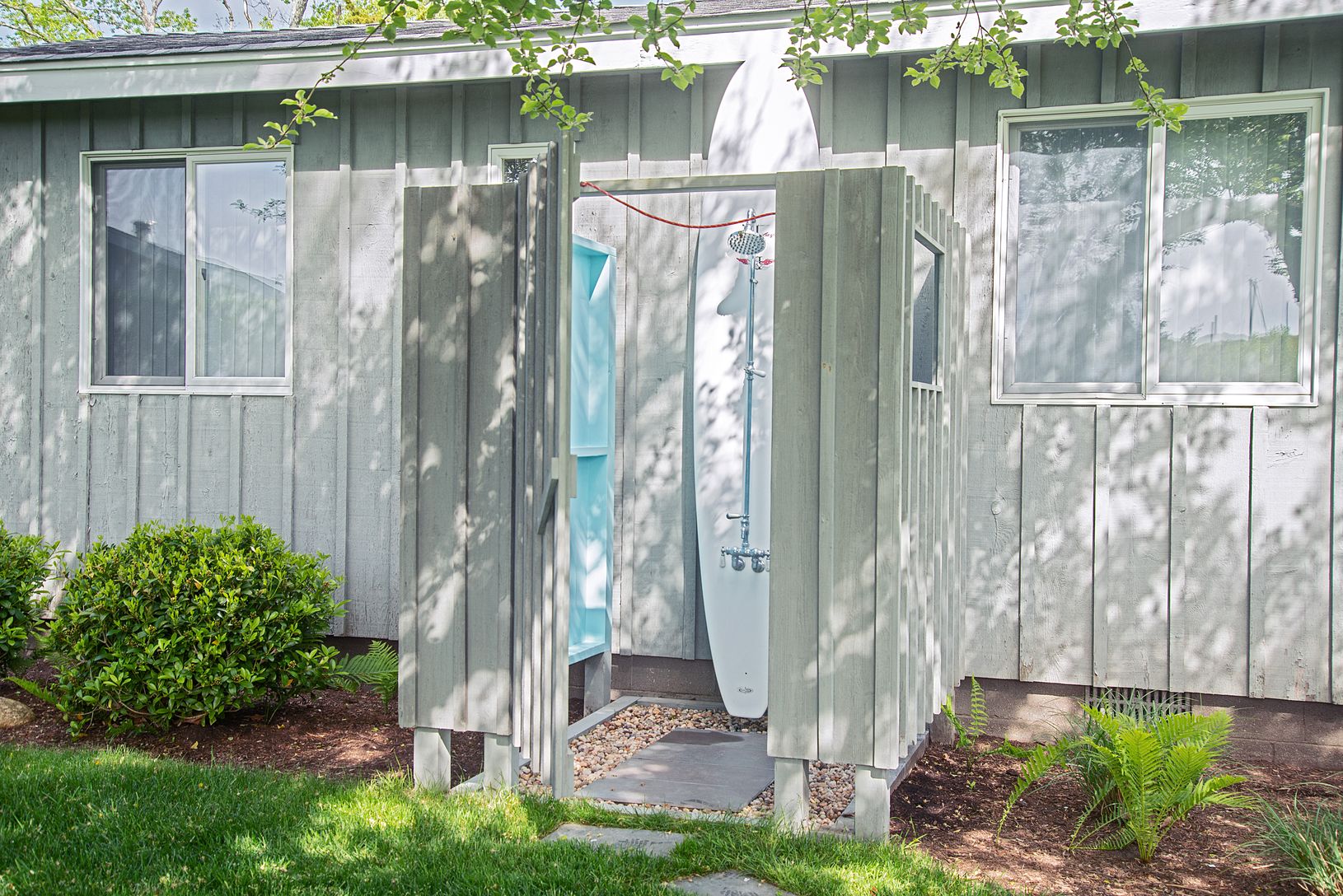 A spacious outdoor shower features a surfboard.